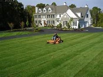 Image of a Person Mowing the Lawn Outside of a House