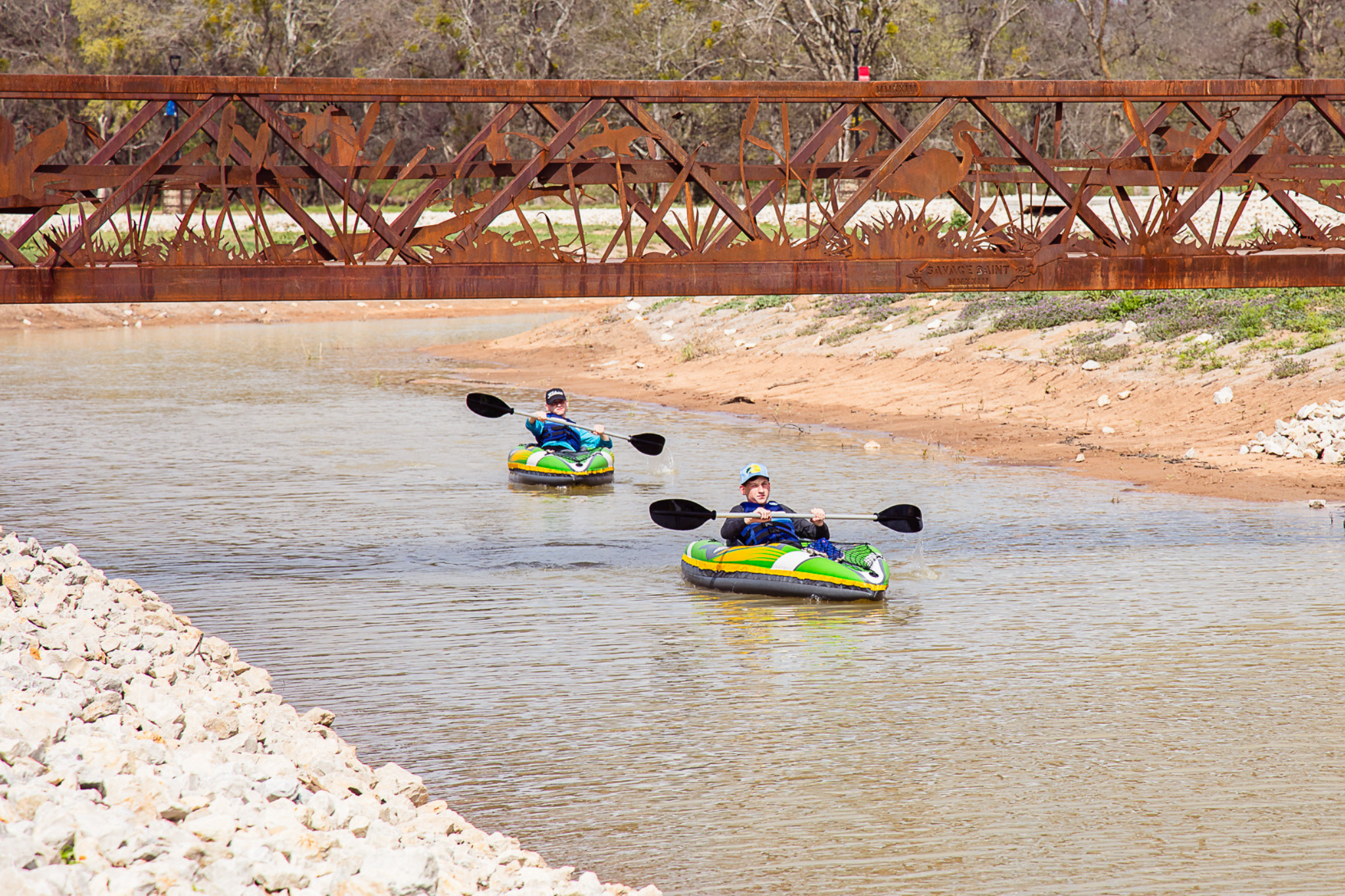 Picture of two kids kayaking in the lake under a bridge