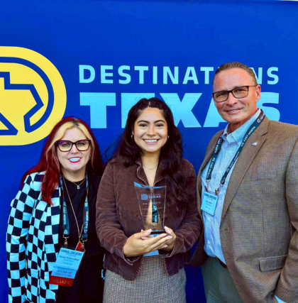 Image of Three People Smiling for a Photo While One Holds an Award